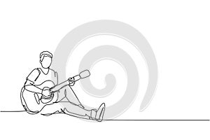 One continuous line drawing of young happy male guitarist sitting relax on the floor while playing acoustic guitar. Musician