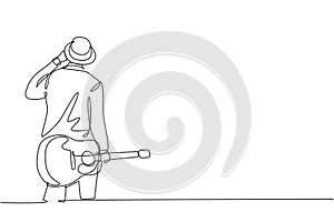 One continuous line drawing of young happy male guitarist wearing hat and holding acoustic guitar on his hand. Modern musician
