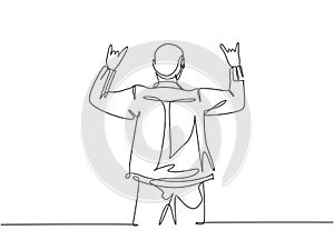One continuous line drawing of young happy male rocker singer giving hand gesture of rock music on concert stage. Trendy musician