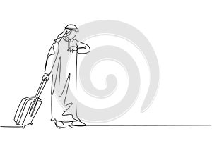 One continuous line drawing of young male muslim businessman staring the watch while holding travel case. Islamic clothing shemag