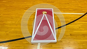 One cornhole board set up on a gym floor close up