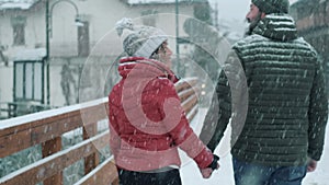 One couple holding hands under the snowing town during winter holiday vacation at mountain. Man and woman walking in outdoor