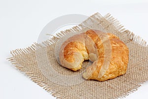 One croissant on spuare frayed burlap