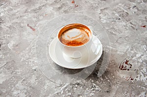 One cup of cappuccino on a gray concrete background.