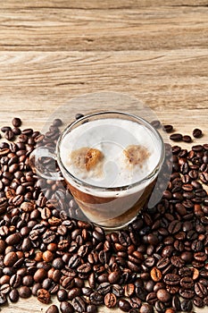 One cup of coffee with milk and coffee beans on wooden surface