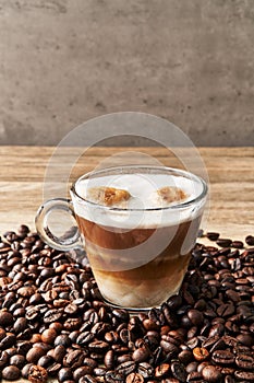 One cup of coffee with milk and coffee beans on wooden surface