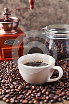 One cup of espresso and coffee beans on wooden surface