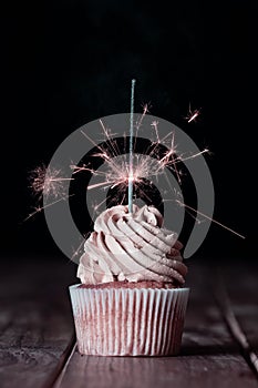 One cupcakes on a table with a sparkle and black background