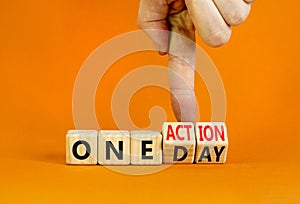 One day and action symbol. Concept words One day and One action on wooden cubes. Businessman hand. Beautiful orange table orange