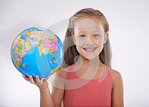 One day Im going to travel around the world. Studio shot of an adorable little girl holding a globe and smiling at the