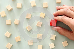 One different red cube block among wooden blocks. Individuality, leadership and uniqueness concept.