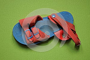 One dirty blue sandal with red leather harnesses