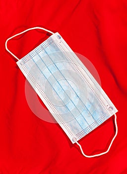 One disposable mask lying on a red fabric