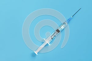 One disposable syringe on a blue background. Space for text