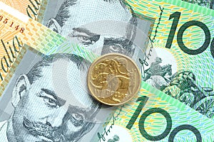 One dollar australian coins on one hundred banknote background