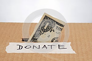 One dollar banknote inserted in a slot of donation box
