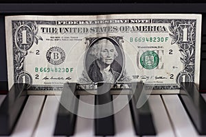 One dollar banknote lying on the piano keys.