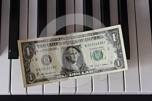 One dollar banknote lying on the piano keys