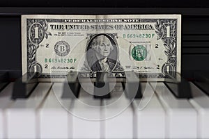 One dollar banknote lying on the piano keys