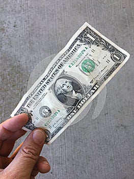 One Dollar Bill Held in Fingers