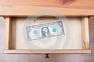 One dollar bill in open drawer