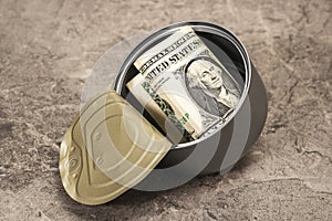 One dollar in a tin can falling on the stone background