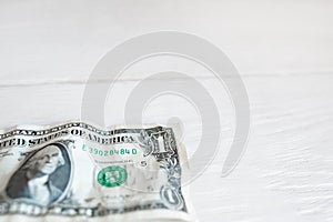 One dollar on white wooden background, free space