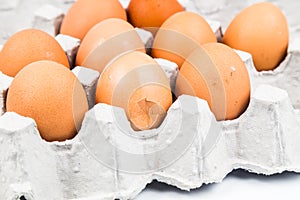 One egg with cracked egg shell with other eggs on tray.