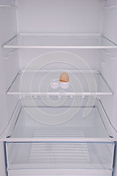 One eggs in open empty refrigerator.