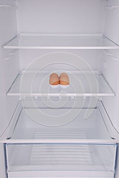 One eggs in open empty refrigerator.