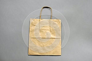 One empty brown shopping bag with handles on gray background with copy space. Recycled paper bag. Mockup for design.