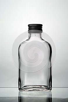 One empty liquor alcohol glass bottles with black cap and  on a grey background