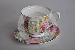 One empty porcelain tea cup with floral pattern and plate on white background.