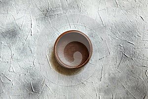 One empty wooden bowl on grey background. Single round salad bowl on stone table with black stains, top view