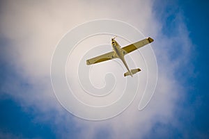 One-engine plane flying under white cloud in blue sky