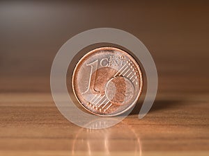 One euro cent standing on a wodden table