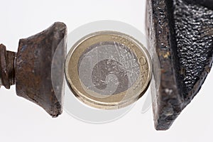 One Euro coin in a black clamp isolated on white