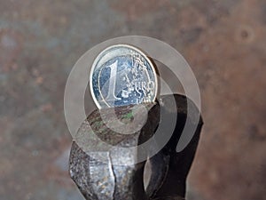 one Euro coin clamped in a pincer. Concept of financial problems , crisis downturn in Europe