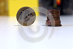 One euro coin and stack of cents on blurred background