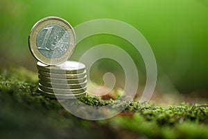One Euro Coin on pile of coins in Nature - Green Money