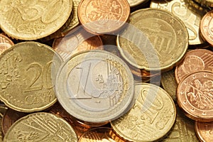 One Euro coin on top of a pile of other Euro coins