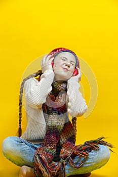 One Expressive Winsome and Smiling Caucasian Blond Girl In Warm Knitted Hat and Scarf While Listening to Music in Wireless