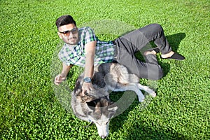 One fashion middle eastern man with beard and fashion hair style is resting and enjoy on beautiful green grass .