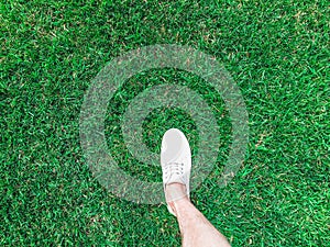 One feet in white sneakers on the grass