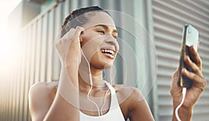 One fit young hispanic woman listening to music with earphones from a cellphone while taking a break from exercise