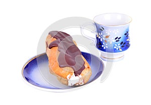 One fresh eclair on blue plate with coffe cups