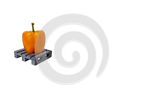 One fresh orange paprika standing on grey mini pallet isolated, white backdrop,large copy space.Sweet yellow bell pepper