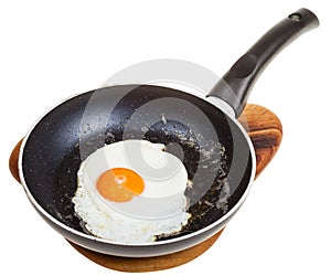 One fried egg in black frying pan isolated
