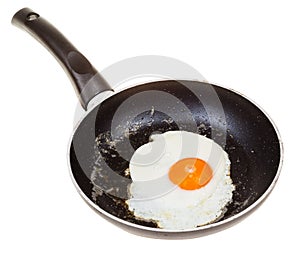 One fried egg in black frypan isolated on white