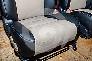 One front seat with combined leather trim in two colors of black and beige, located on the workbench in the workshop for repair